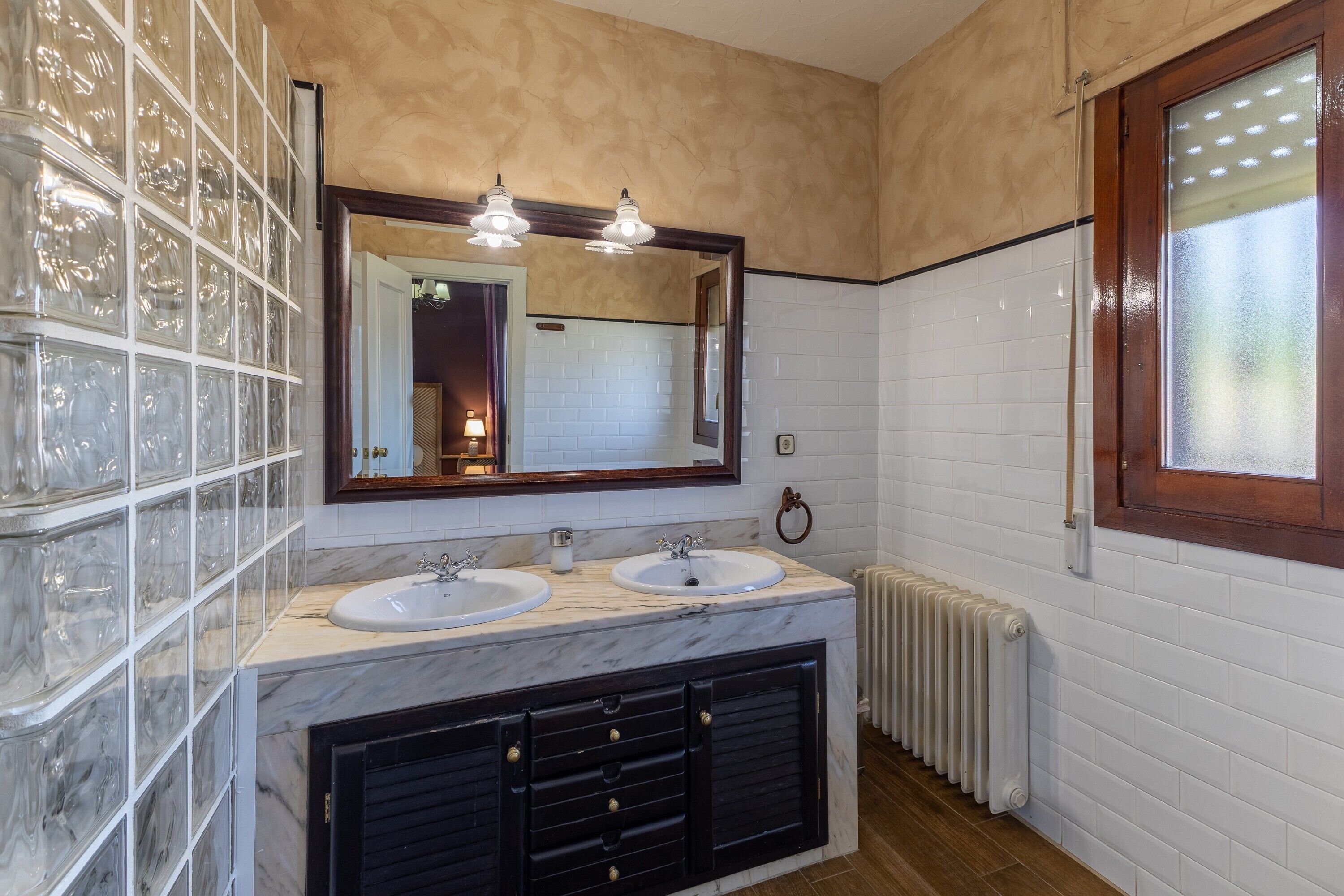 A bathroom with two sinks, a large mirror, and a radiator.