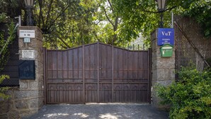 Una entrada protegida por un muro de piedra, una reja metálica y un letrero que indica una zona de uso turístico.