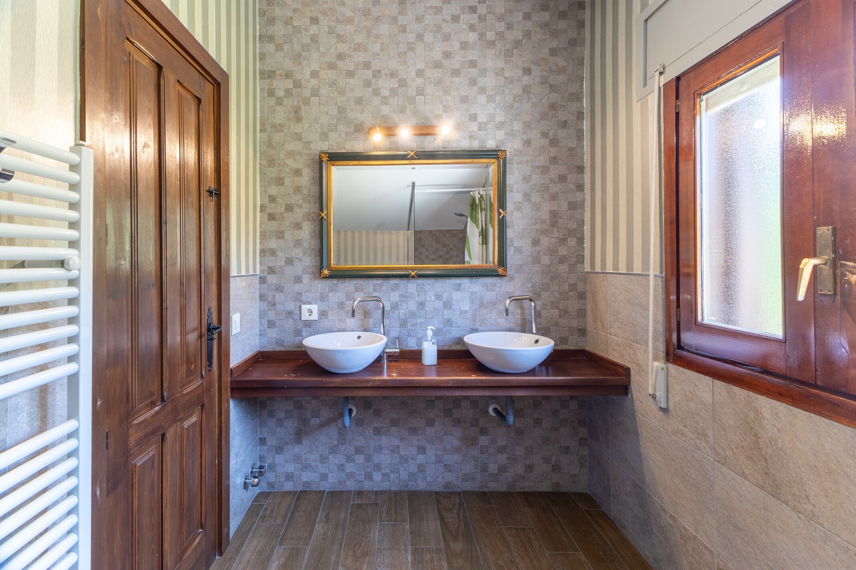 A bathroom with two sinks, a mirror, and a shower.