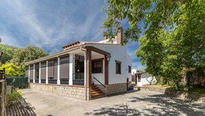 Una casa de una sola planta con porche cubierto, base de piedra y escalera de acceso a la entrada.