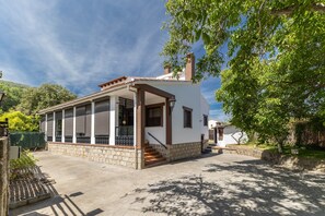 A single-story house with a covered patio, stone foundation, and a staircase leading to the entrance. - Holiday Home 'Viria' with Mountain Views, Wi-Fi and Air Conditioning (Navaluenga)