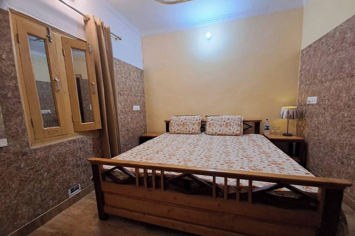 A bedroom with a wooden bed, a nightstand, a mirror, and a window with curtains.