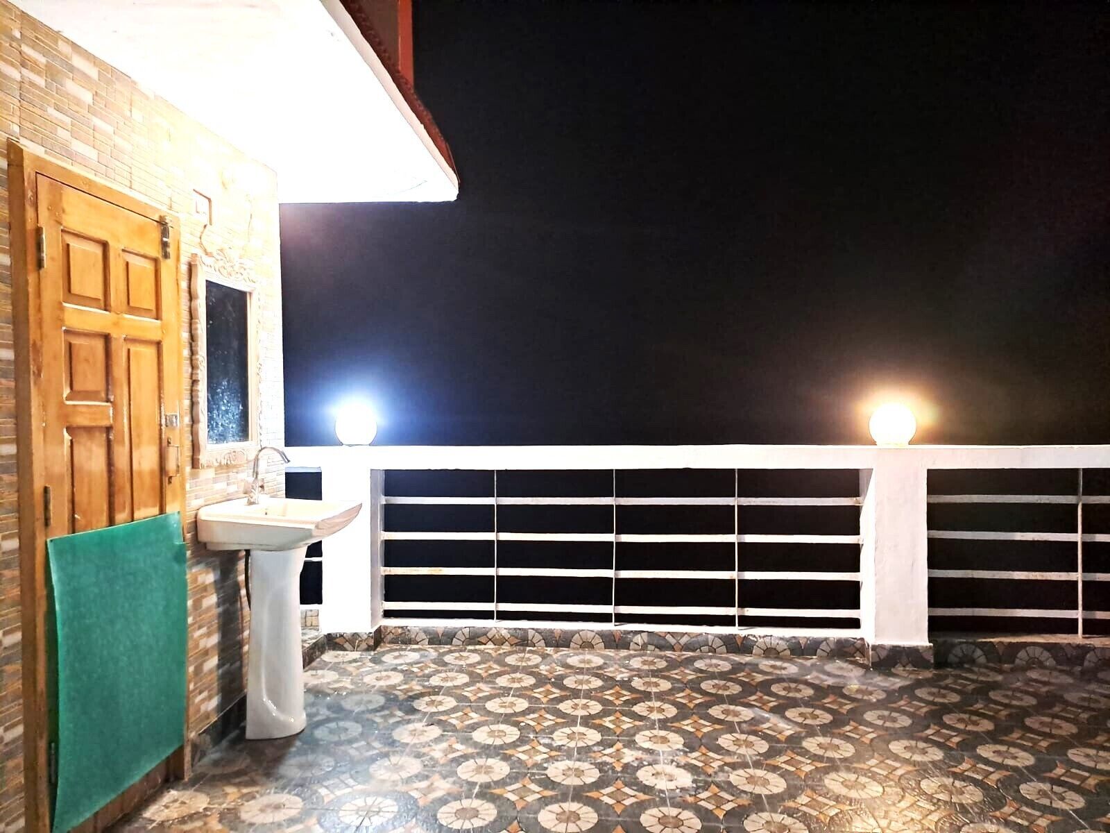 A balcony with a tiled floor, a sink, and a towel hanging on the wall.