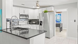 A modern kitchen with white cabinets, stainless steel appliances, and a central island. - Intervillas Florida - Villa Bluesky at the Lake (Cape Coral)