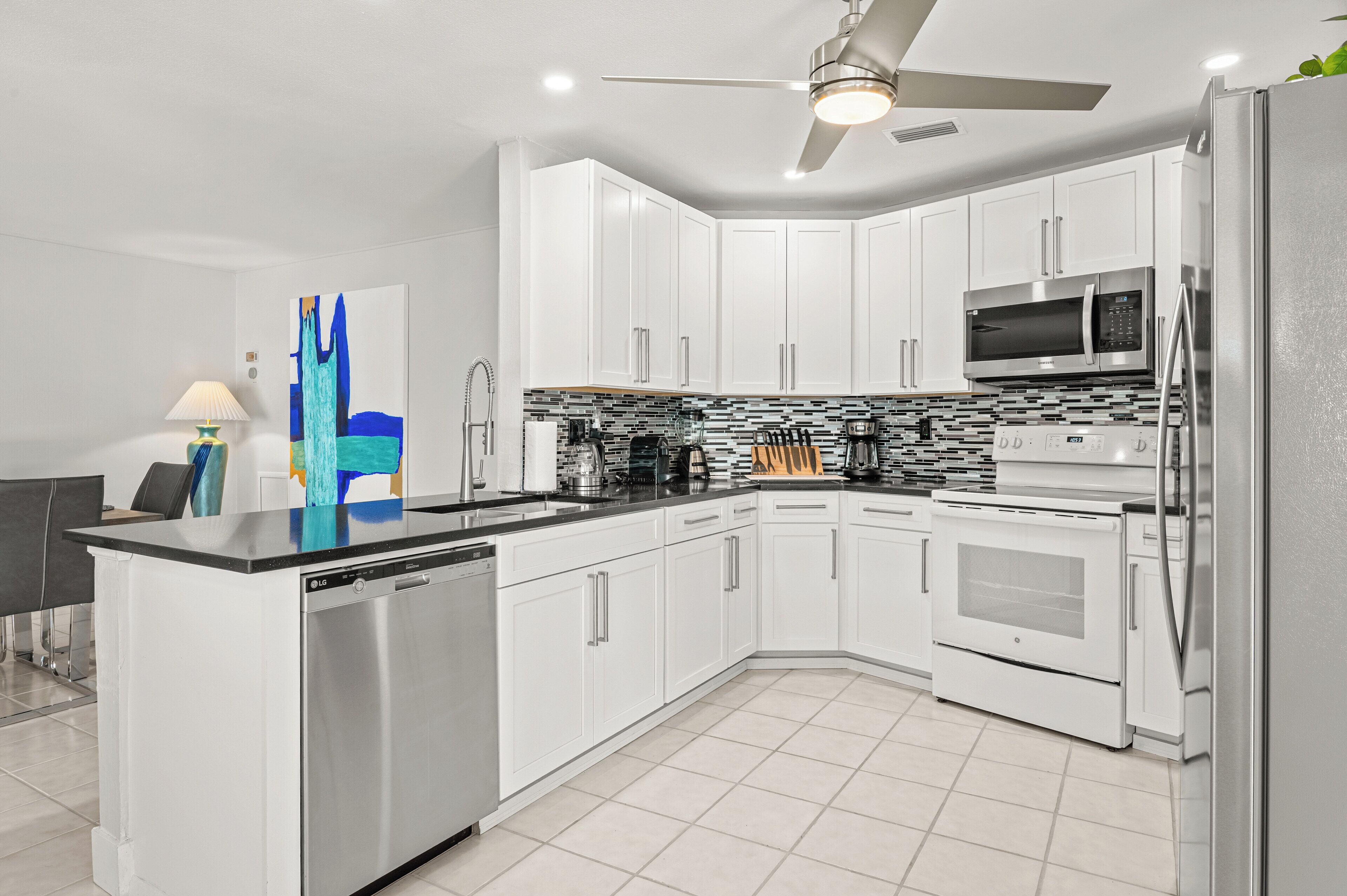 A modern kitchen with white cabinets, stainless steel appliances, and a tiled backsplash.