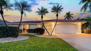A residential house with a well-maintained lawn, palm trees, and a garage. - Intervillas Florida - Villa Bluesky at the Lake (Cape Coral)