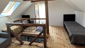 Una habitación pequeña estilo ático con una litera de madera, un escritorio pequeño y una ventana.
