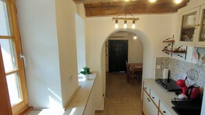 Una cocina con vigas de madera, un comedor y vistas a través de un arco.