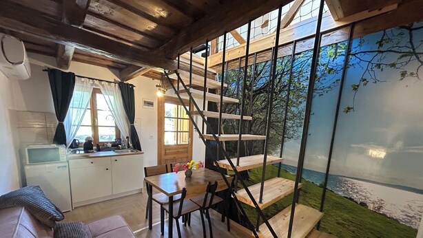 Un interior acogedor con una escalera de madera, un comedor y una cocina.