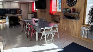 Een ruime keuken met een eethoek, houten wanden, een grote klok en een televisie.