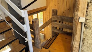 Een houten trap met een touwspijbel, een houten muur en een stenen muur.