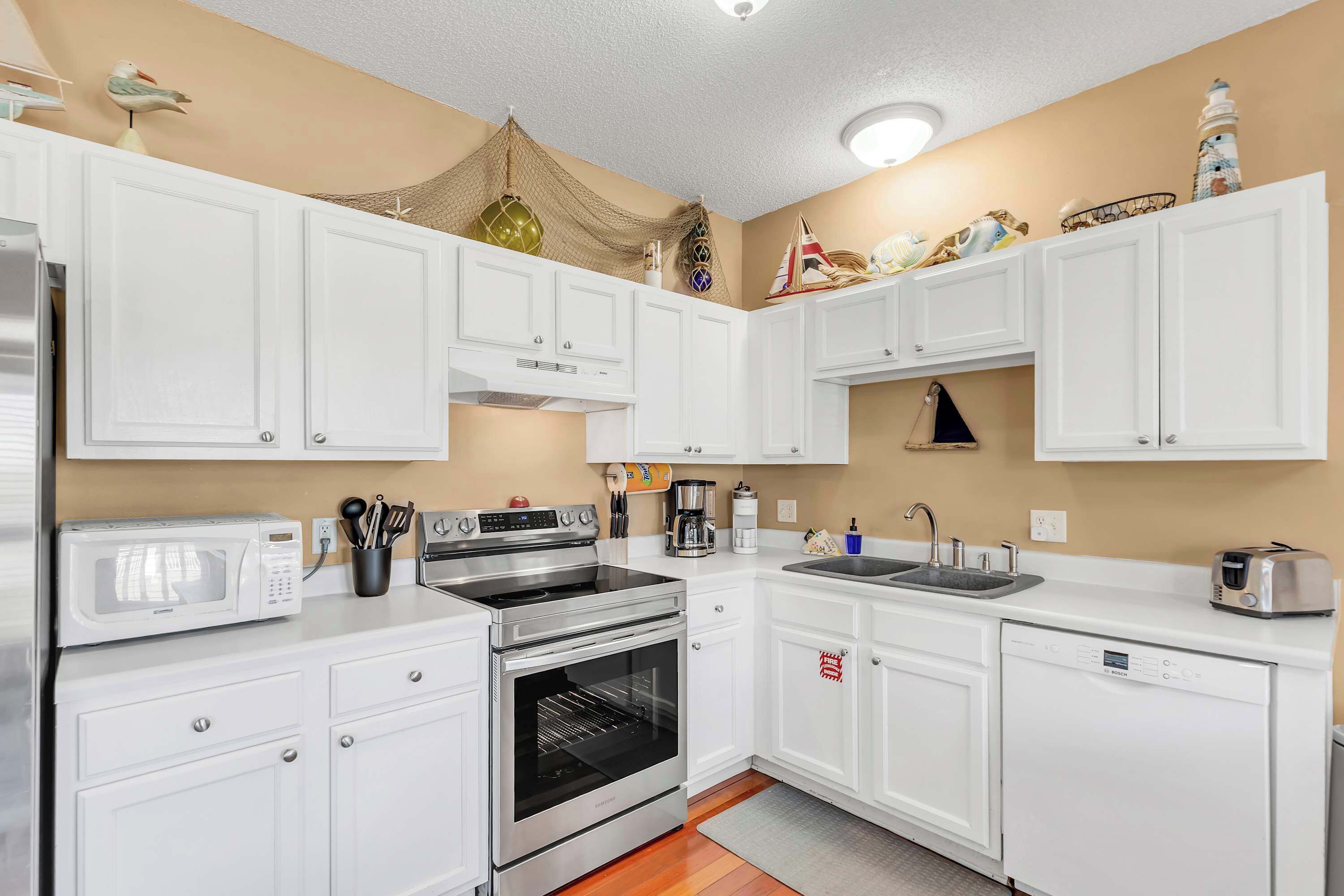 A kitchen with white cabinets, stainless steel appliances, a microwave, oven, and dishwasher.