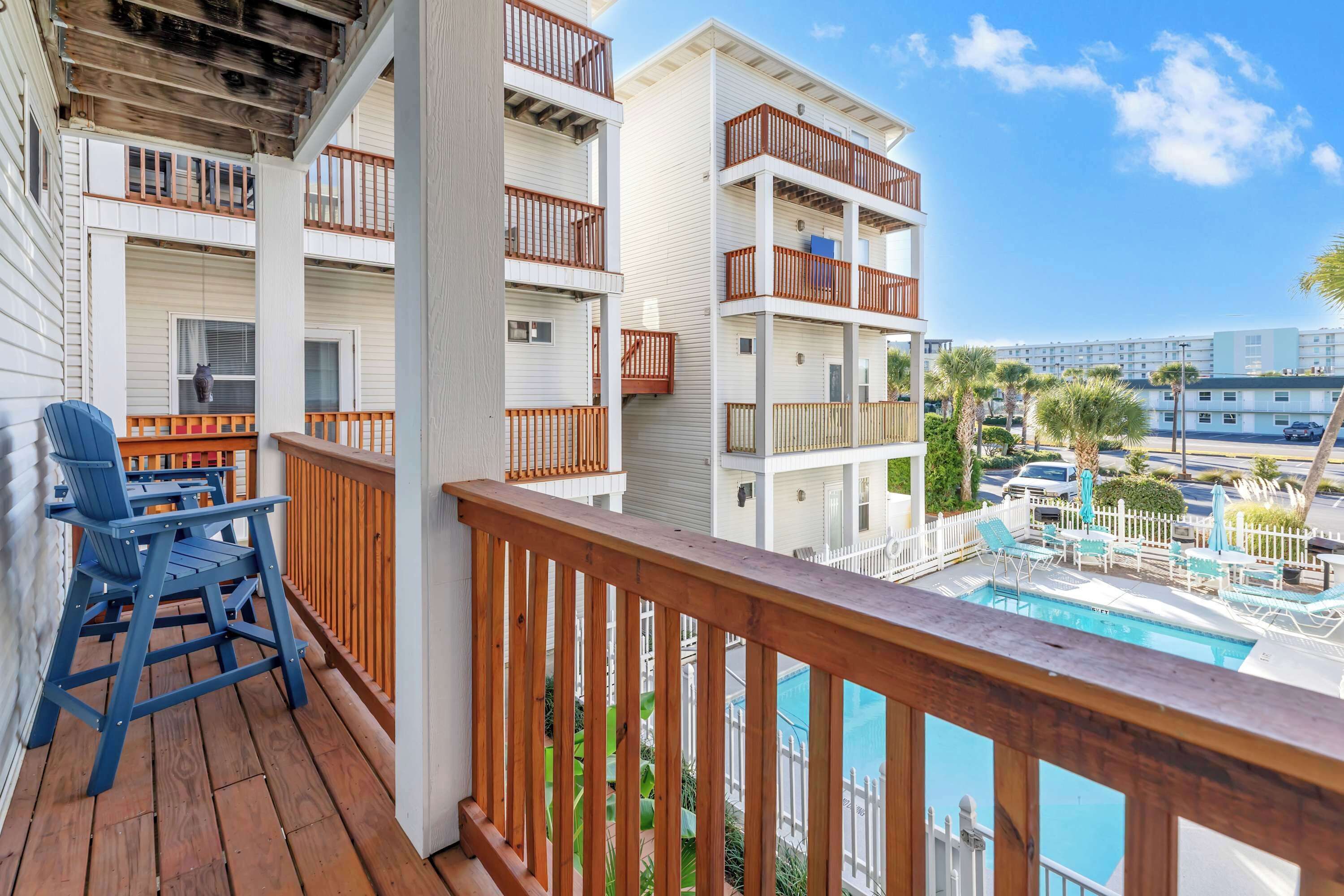 Varanda com guarda-corpos de madeira, piscina e vista para outros edifícios.