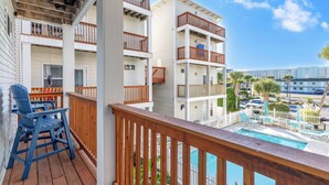 Un balcon avec des balustrades en bois, une piscine et une vue sur d’autres immeubles.