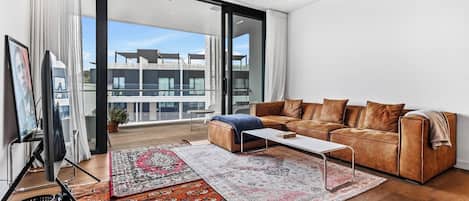 A modern living room with a leather sofa, a coffee table, and two rugs.