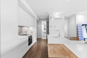 Eine moderne Küche mit weißen Schränken, einer Marmor-Spritzschutzwand und Holzboden.