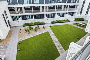 Ein modernes Gebäude mit einem Dachgarten, der Gras, Pflanzgefäße und Sitzbereiche bietet.