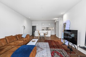 Ein modernes Wohnzimmer mit einem braunen Ledersofa, einem Couchtisch und einem Fernseher.
