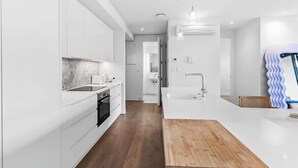 Een moderne keuken met witte kastjes, een houten aanrecht en een centraal kookeiland.