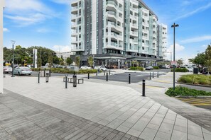 Een modern hotel met een glazen gevel, een overdekte ingang en een parkeerplaats met paaltjes.