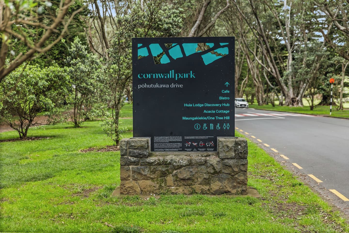 Un panneau indiquant l’entrée du parc de Cornwall, avec une liste des commodités disponibles, notamment un café, un bistrot et un espace dédié à la découverte.