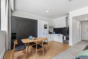 A compact kitchen with white cabinets, a black countertop, and a microwave. - Sleeps 4! + Parking, Pool and Gym by Zodiak Stays (Central Auckland)