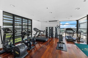 Ein modernes Fitnessstudio mit verschiedenen Trainingsgeräten, großen Fenstern und Blick auf die Stadt.