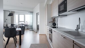 Eine moderne Küche mit integriertem Mikrowellenherd, Spüle aus Edelstahl und Holzschränken.