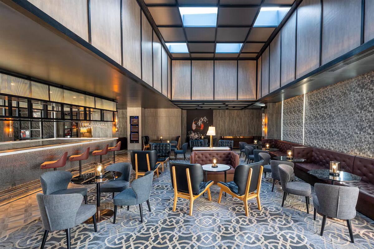 A modern lounge area with seating arrangements, a bar, and a patterned floor.