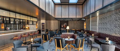 A modern lounge area with seating arrangements, a bar, and a patterned floor.