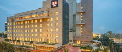 Un hotel moderno con varios pisos, un llamativo letrero 'RED' y una fachada bien iluminada.