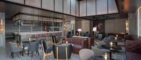 A modern lounge area with seating arrangements, a bar, and a fireplace.