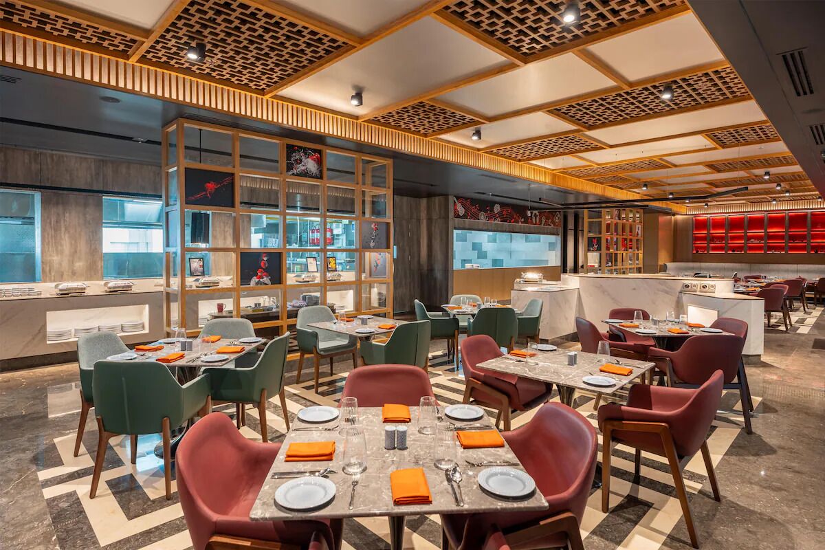 A modern restaurant with multiple dining tables and chairs, a bar area, and a decorative ceiling.