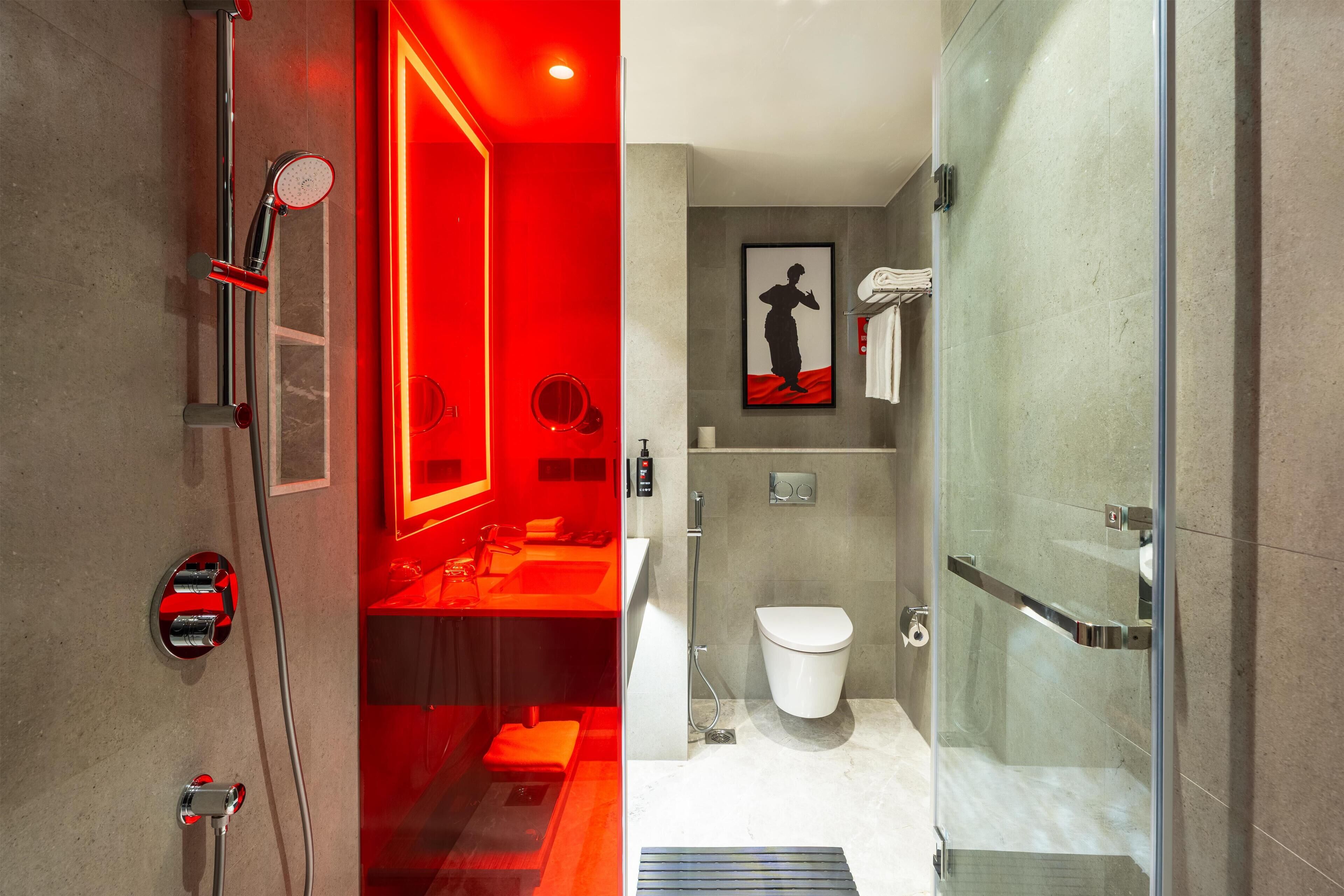 A modern bathroom with a glass shower enclosure, a white toilet, and a red-lit vanity area.