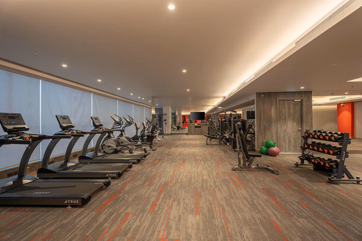 Un gimnasio moderno con cintas de correr, elípticas y equipamiento de levantamiento de pesas.