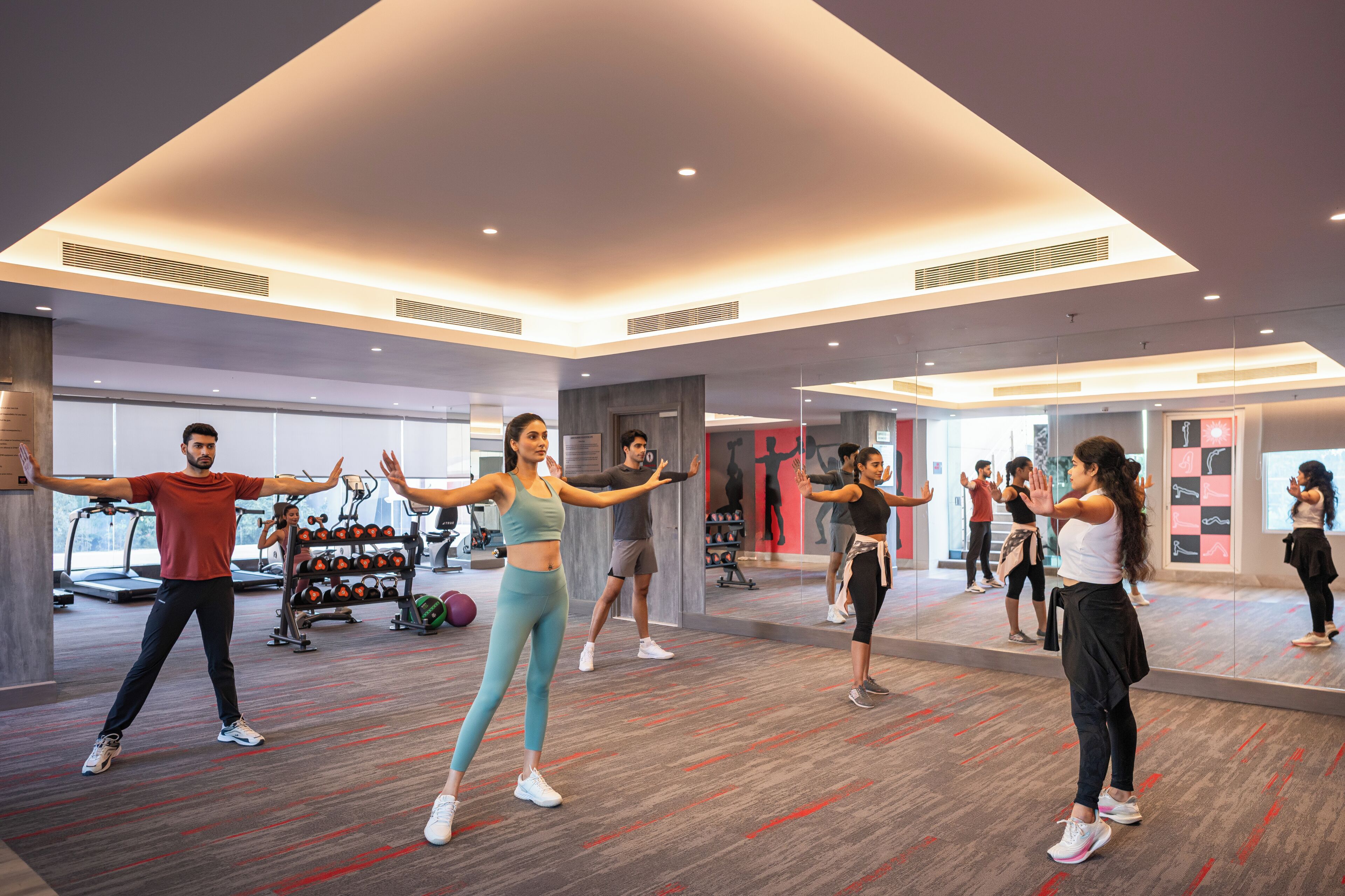 Une salle de sport moderne, dotée d’appareils d’exercice, de miroirs et d’un aménagement spacieux.