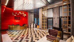 A modern lobby with a reception desk, a patterned floor, and a seating area with a sofa and armchair. - Radisson RED Indore (Indore)