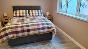 A bedroom with a bed, two bedside tables, a window, and a patterned rug. - Greenway Getaway. Lovely central 3-bedroom townhome in peaceful Westport (Westport)
