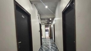 A hallway with marble flooring and doors on both sides. - Hotel Awadh Pearl (Lucknow)