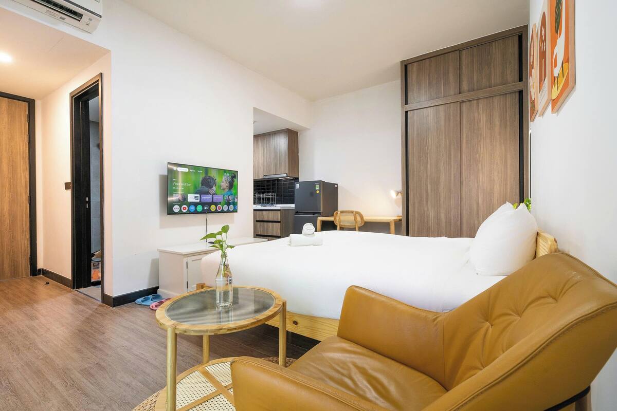 Ein Hotelzimmer mit Bett, Fernseher, einem kleinen Tisch mit Vase und einem Ledersessel.