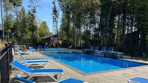 Una piscina con sillas reclinables azules y un edificio de madera al fondo.