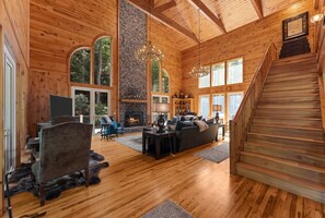 Ein geräumiges Wohnzimmer mit Kamin, Holzböden und einer Treppe.