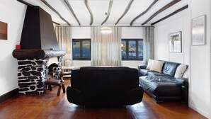 Un salon avec une cheminée en pierre, un canapé en cuir noir et un banc en bois.