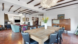 Un vaste espace dédié à la salle à manger, avec une table et des chaises en bois, un lustre et un grand vase orné de plantes.