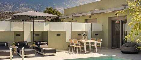 A modern outdoor pool area with lounge chairs, a table, and a pergola.