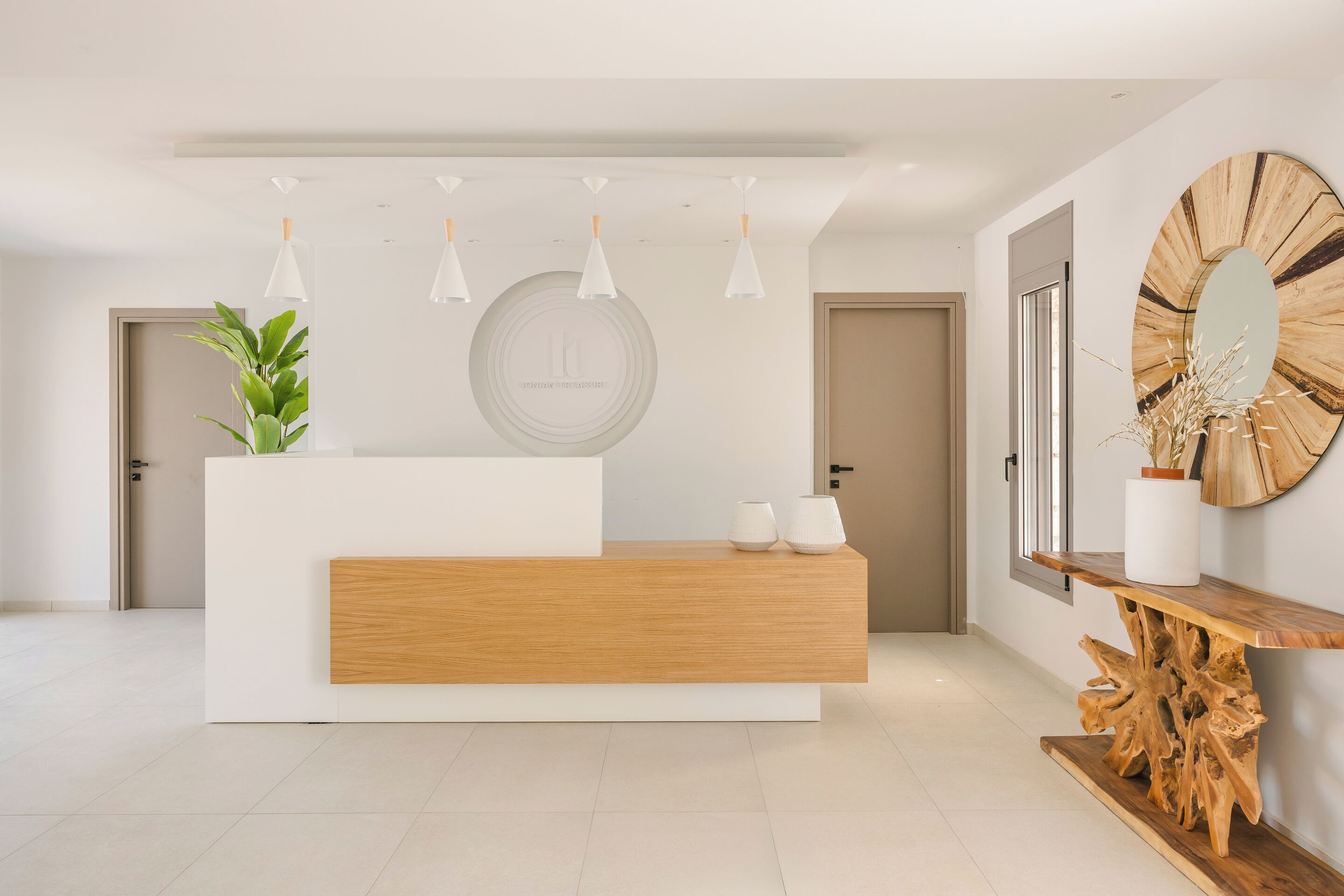 A modern reception desk with a wooden accent, a potted plant, and a circular wall art piece.