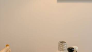A wooden table with a white textured lamp, a framed abstract art piece, a white vase, and two metallic salt and pepper shakers.