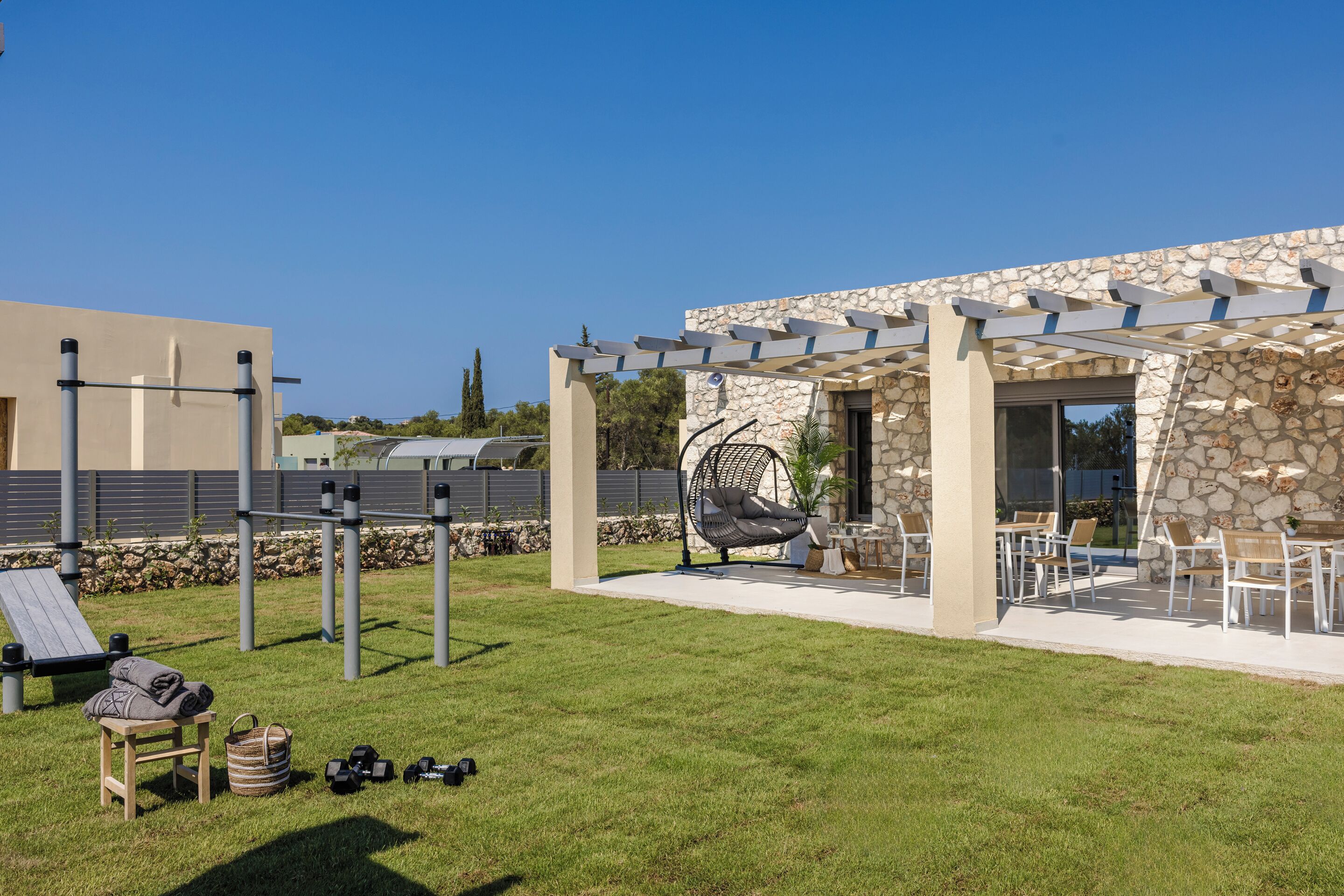 An outdoor patio area with a stone wall, a hanging chair, and outdoor furniture.