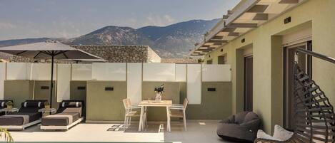 A rooftop pool area with lounge chairs, a dining table, and a hanging chair.