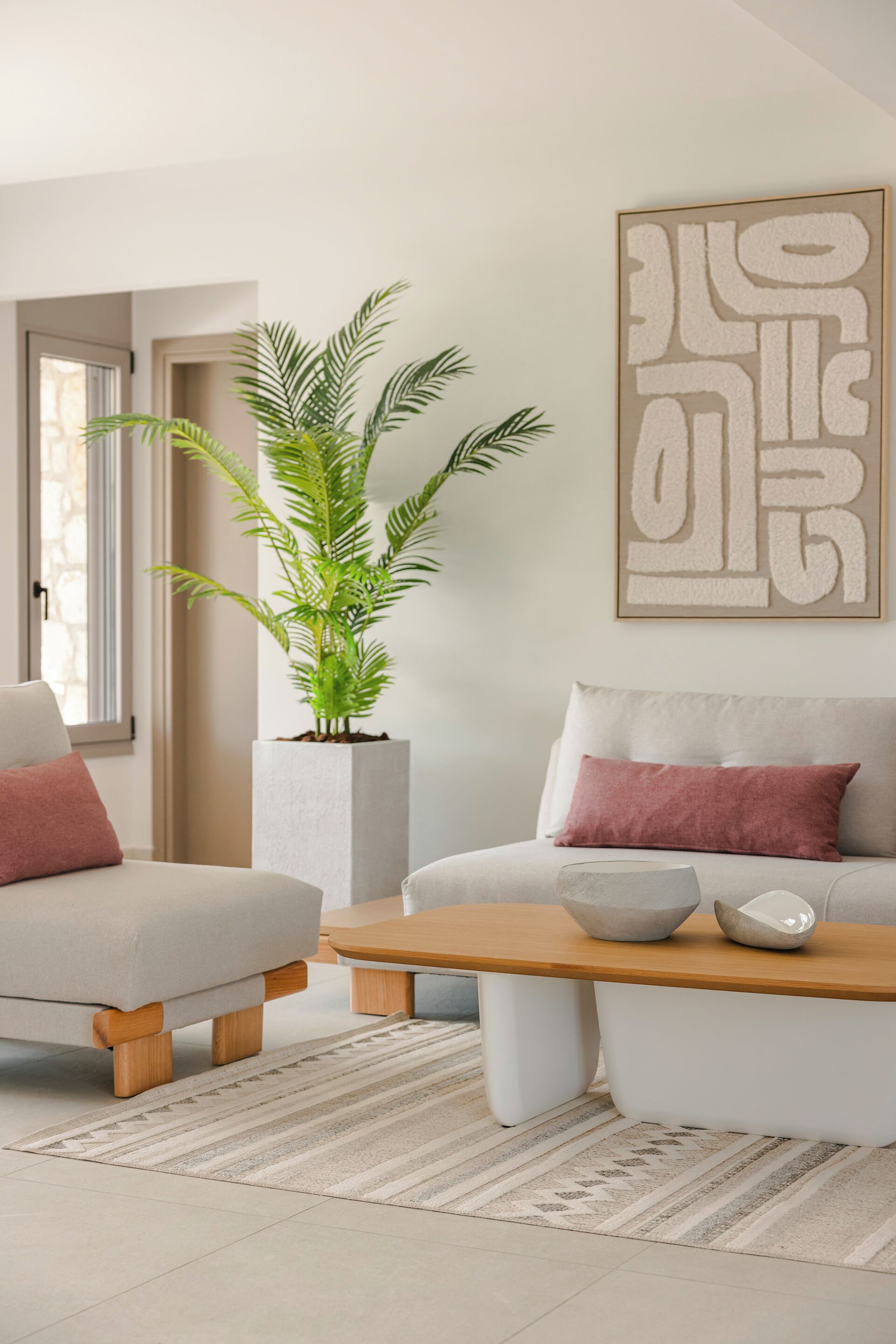 A modern living room with a sofa, armchair, coffee table, and a potted plant.